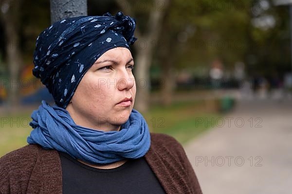 Portrait of a Latin woman undergoing cancer treatment with her head covered by a scarf with an expression of strength,