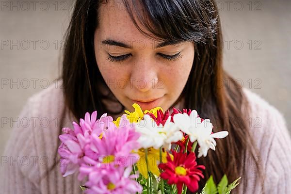 Close-up portrait of a young Latin woman holding a bouquet of flowers,