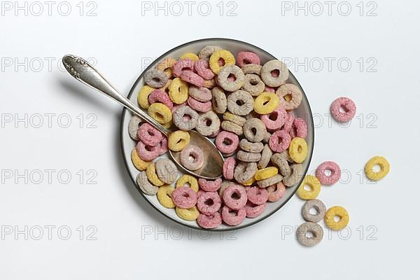 Fruit-flavoured cereal rings in bowl and spoon, children's breakfast