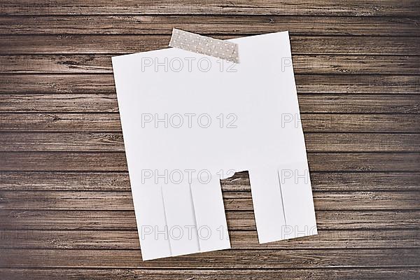 White empty tear-off stub paper note without text on wooden wall,