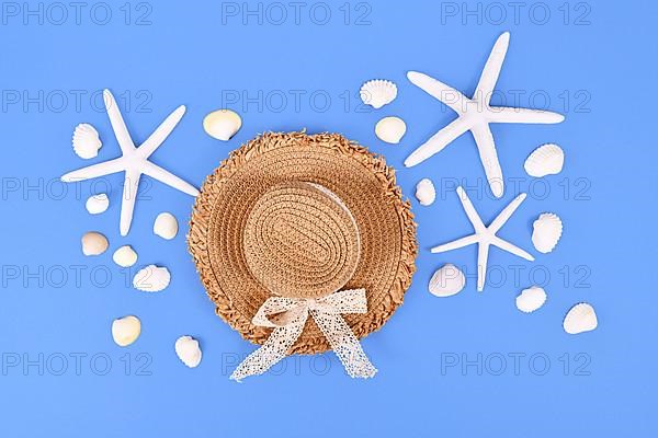 White starfish, seashells and summer straw hat on blue background