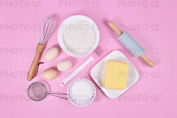 Cake dough ingredients and baking tools on pink background,