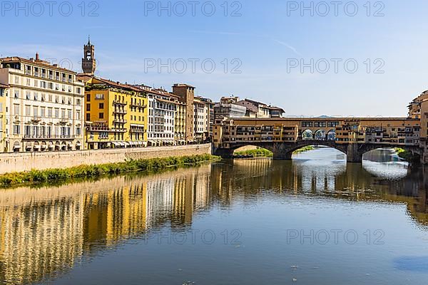 Pastel-coloured house facades reflected in the water of the river Arno, view of the Ponte Vecchio