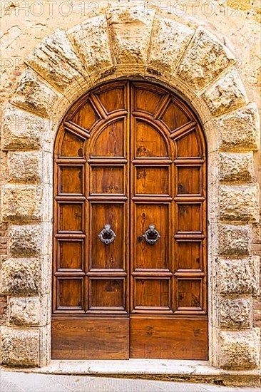Round arched house entrance door, framed with light-coloured stones