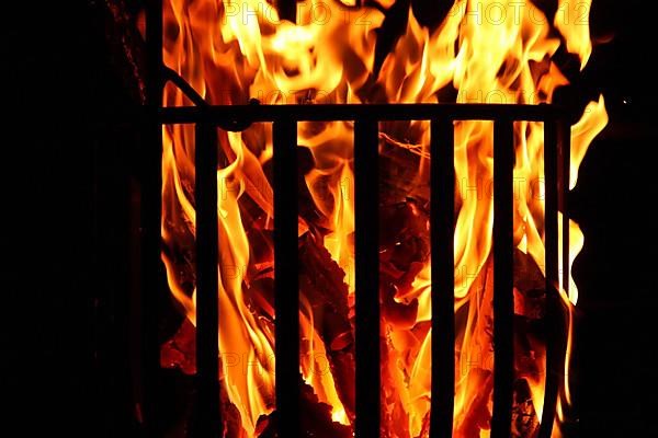 Metal fire basket with burning wood at night,