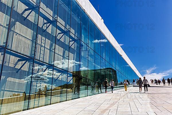 Pedestrians on the forecourt reflected in the glass facade of the opera house, inclined plane