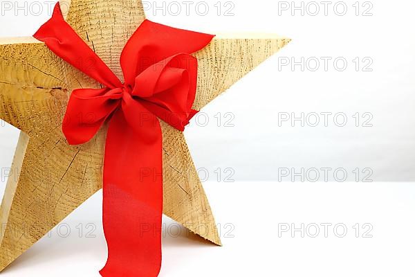 Christmas wooden star with a red bow cut out on a white background,