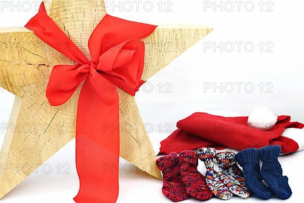 Christmas wooden star with a red bow isolated against a white background, Self-knitted socks on the side