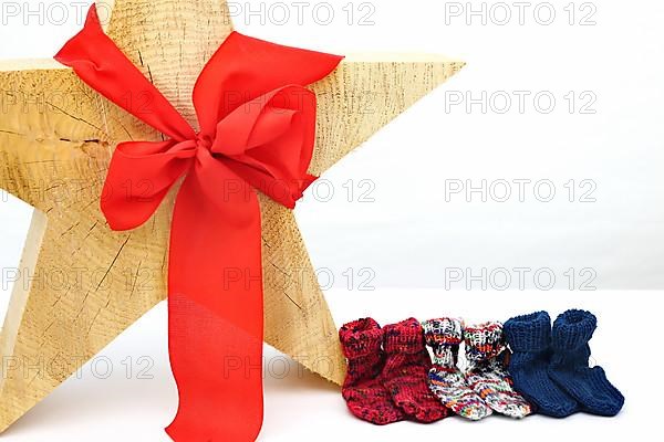 Christmas wooden star with a red bow isolated against a white background, Self-knitted socks on the side