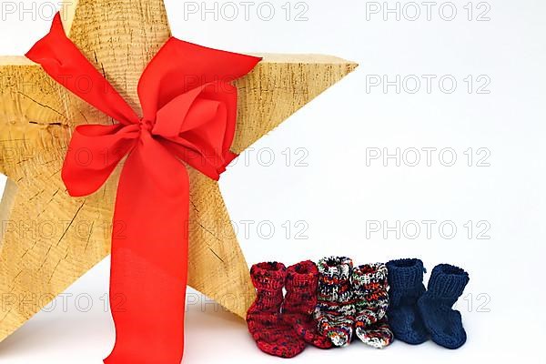 Christmas wooden star with a red bow isolated against a white background, Self-knitted socks on the side