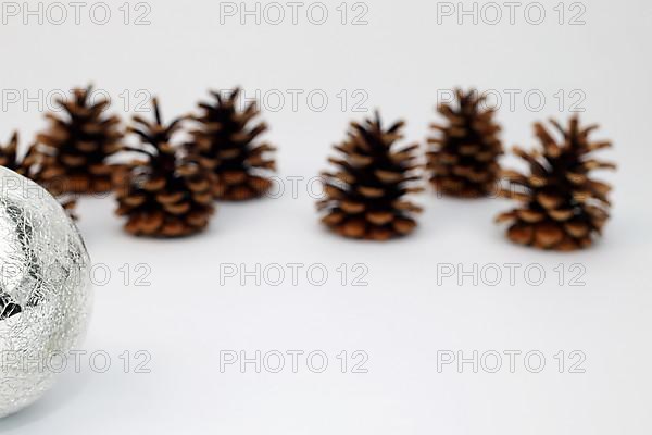 Silver Christmas tree ball and fir cone or pine cone cropped against white background with sharpening gradient,