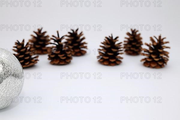 Silver Christmas tree ball and fir cone or pine cone cropped against white background with sharpening gradient,