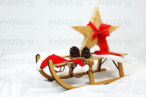 Christmas wooden star with a red bow on a sleigh cut out against a white background,