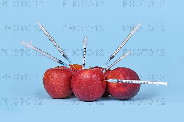 Multiple apple fruits being injected with syringes. Concept for genetically modified organism,