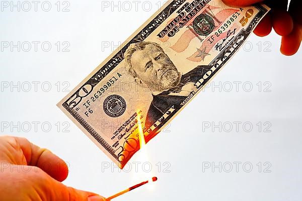 Lighting a fifty dollar note on fire and burning it. Released against a white background,