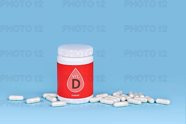 Vitamin D food supplement with container with pills on blue background,