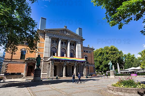 Pedestrians in front of National Theatre decorated with rainbow flag, sign of solidarity