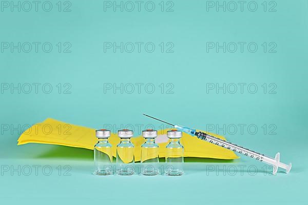 Corona booster vaccine concept with 4 vials with syringes and certificate of vaccination in background with copy space,