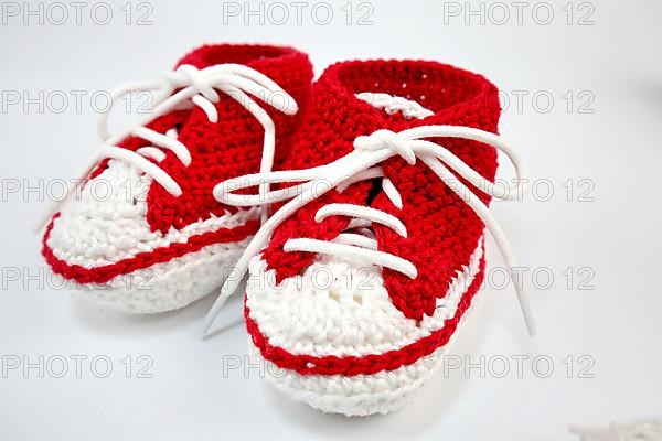 Baby shoes or crochet shoes in red and white isolated against a white background,