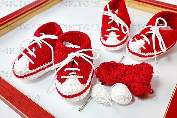 Baby shoes or crochet shoes in red and white isolated against a white background,