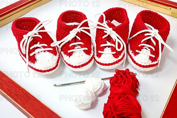 Baby shoes or crochet shoes in red and white isolated against a white background,