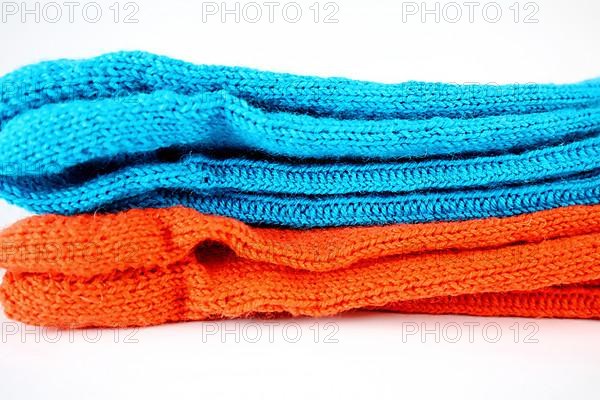 Self-knitted socks made of wool isolated against a white background in orange and blue,