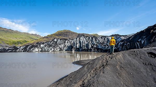 Tourist standing on the lakeshore, glacial fracture on glacier tongue with lake