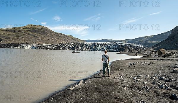 Tourist standing on the lakeshore, glacier tongue and lake