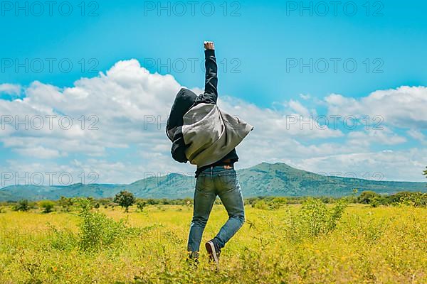 Man from back jumping in a nice field, Rear view of man jumping in the grass raising fist