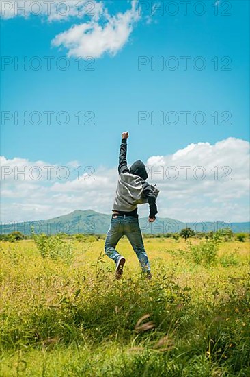 Concept of a free person jumping and raising his arm, Free person jumping with happiness in the field