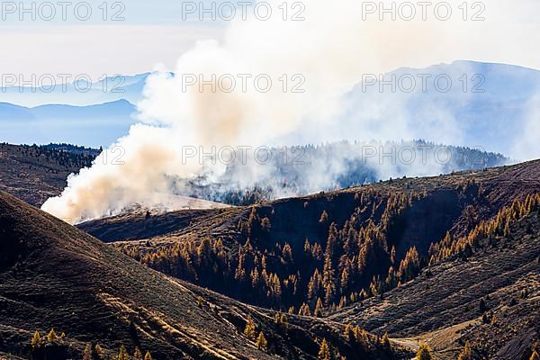 Rising smoke in autumnal landscape, skiing and hiking area Merano 2000