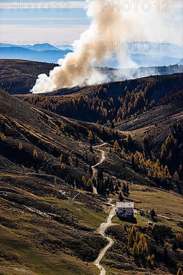 Rising smoke in autumnal landscape, in front the Merano Hut