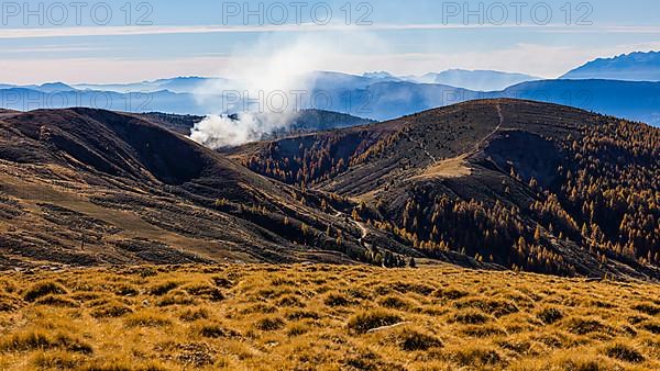 Rising smoke in autumnal landscape, skiing and hiking area Merano 2000
