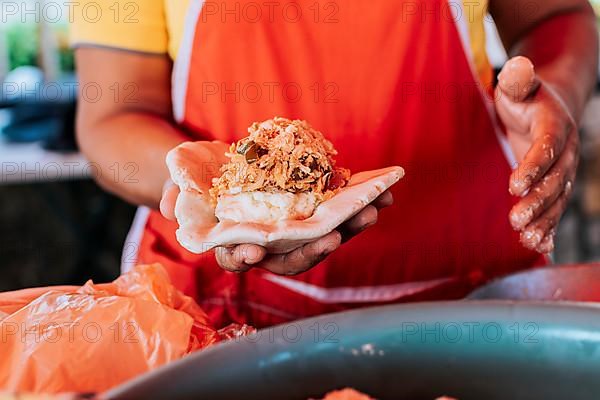 Saleswoman showing traditional raw pupusa. Elaboration of traditional pupusas, elaboration of the dough for traditional pupusas