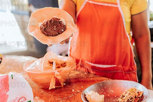 Hands of a vendor showing the process of elaboration of the traditional pupusa. Elaboration of traditional pupusas, Preparation of the dough for traditional Nicaraguan pupusas