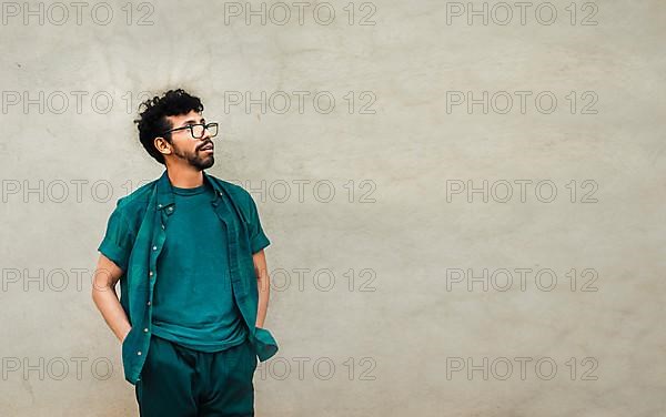 Thoughtful person looking up with copy space, pensive handsome man leaning on a wall looking up