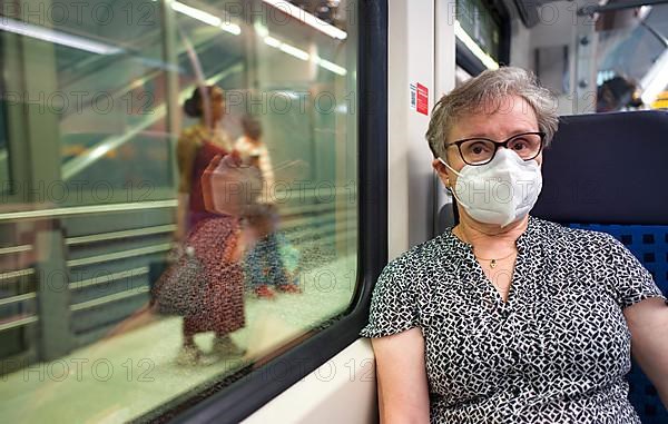 Older woman with mouth mask, sitting in S-Bahn