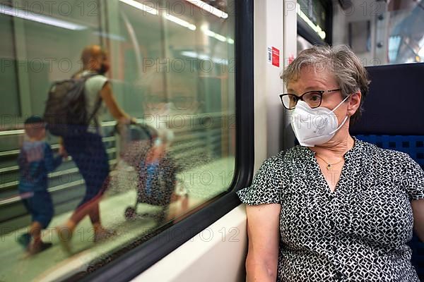 Older woman with mouth mask, sitting in S-Bahn