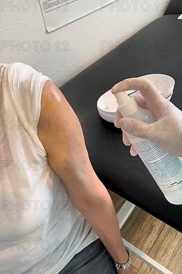 Patient's arm is disinfected by doctor's assistant with medical disinfectant spray Upper arm in front of injection for vaccination Booster against Covid-19 Corona virus Corona virus,