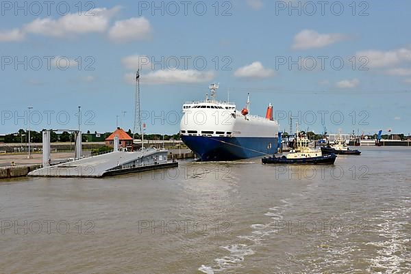 Tugboats move a special ship loaded with cars in the outer harbour, Emden