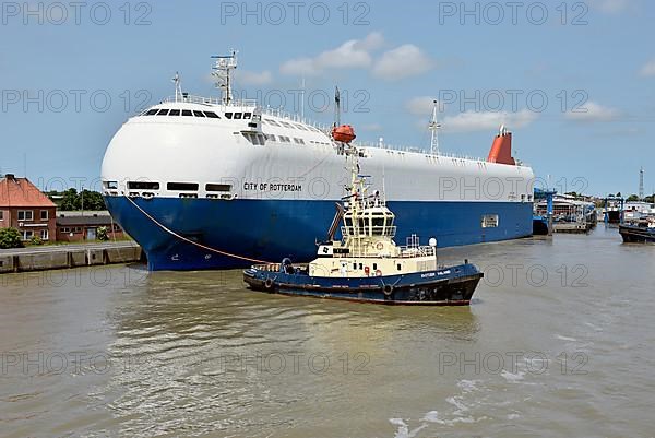 Tugboats move a special ship loaded with cars in the outer harbour, Emden