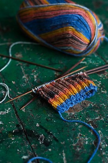 Handwork, knitted sock with knitting needles and wool