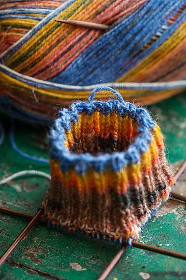 Handwork, knitted sock with knitting needles and wool