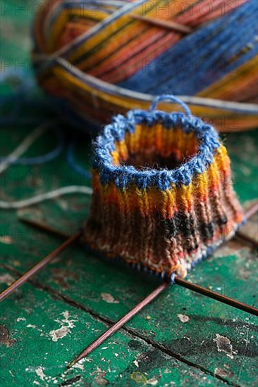 Handwork, knitted sock with knitting needles and wool