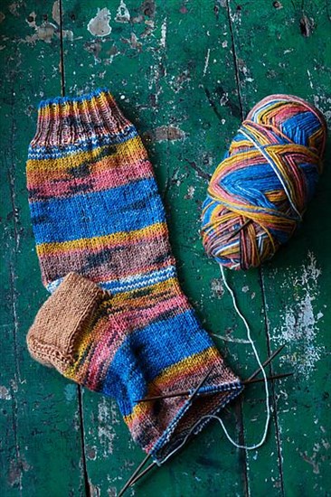 Handwork, knitted sock with knitting needles and wool