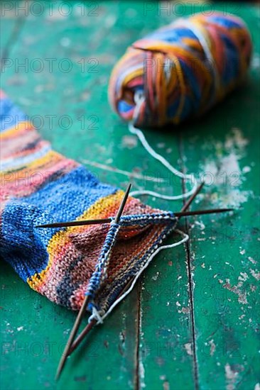 Handwork, knitted sock with knitting needles and wool