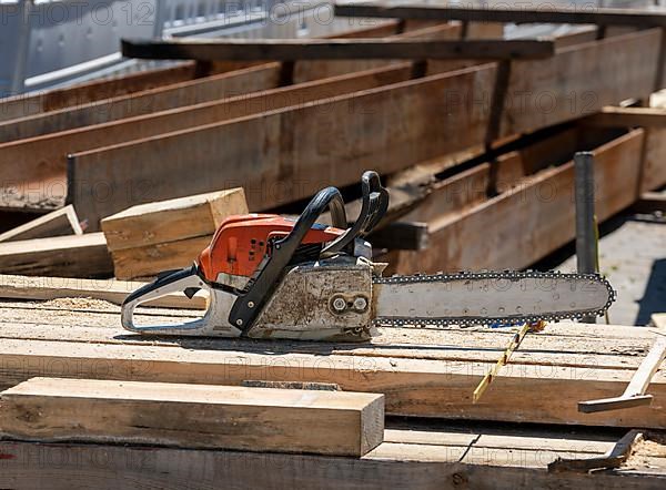 Wood pile with chain saw at a road construction site, Berlin