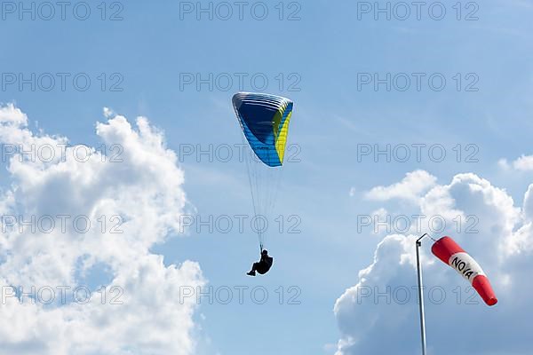 Paraglider in front of cloudy sky, wind vane