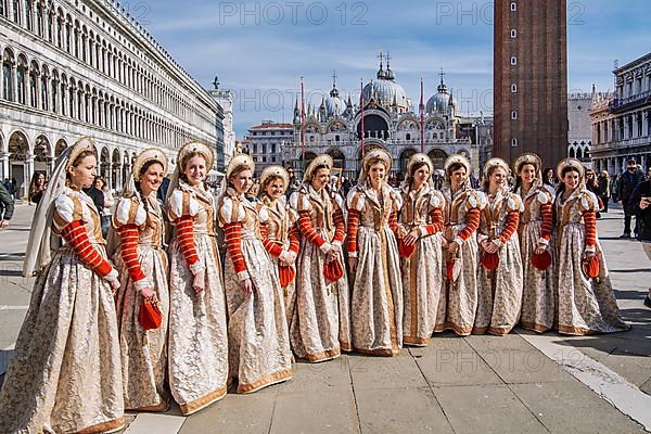 Group of woman in Renaissance robes on St Mark's Square with St Mark's Basilica, Venice