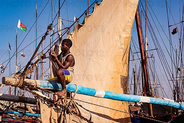 Man sitting on the yard of a fishing boat in the Arab quarter, yard sail behind